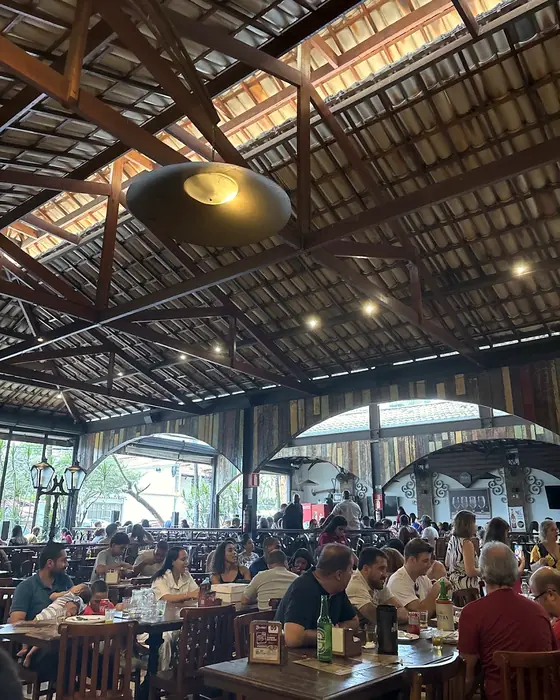 O salão cheio de gente, com as vigas de madeira do telhado