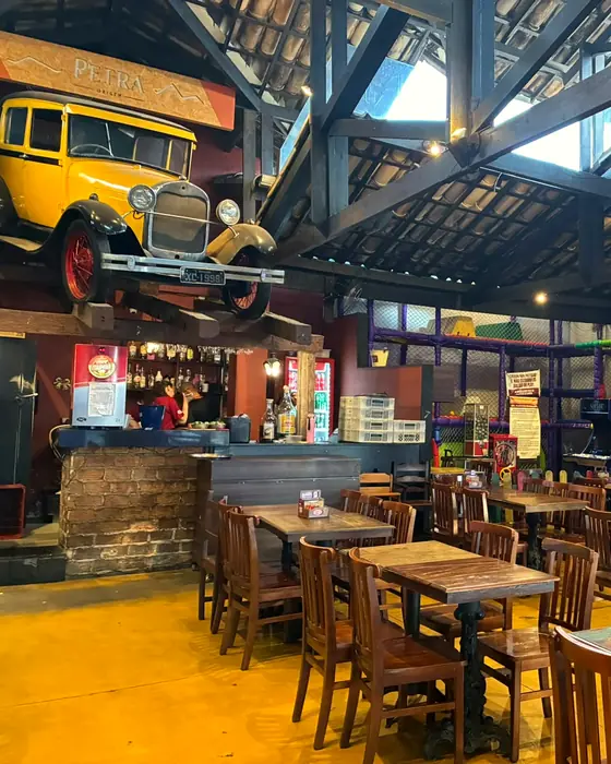 O salão de Santa Inês de dia, com as mesas de madeira e o calhambeque amarelo em cima do bar